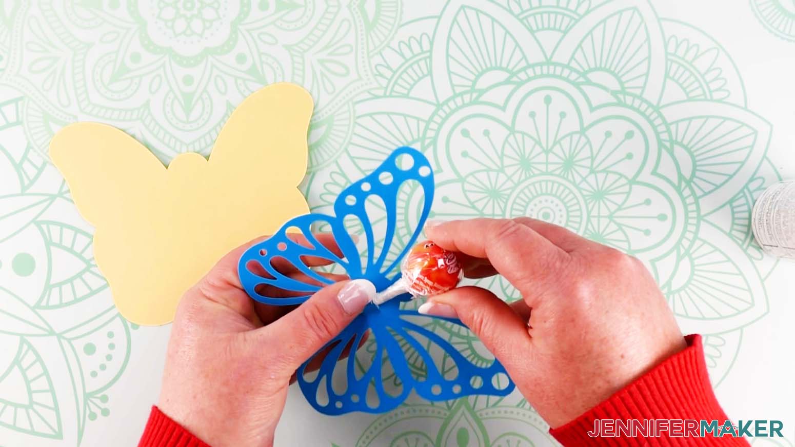 Placing the lollipop stick in the butterfly DIY lollipop holder slit to curve the paper before glueing the layers together.