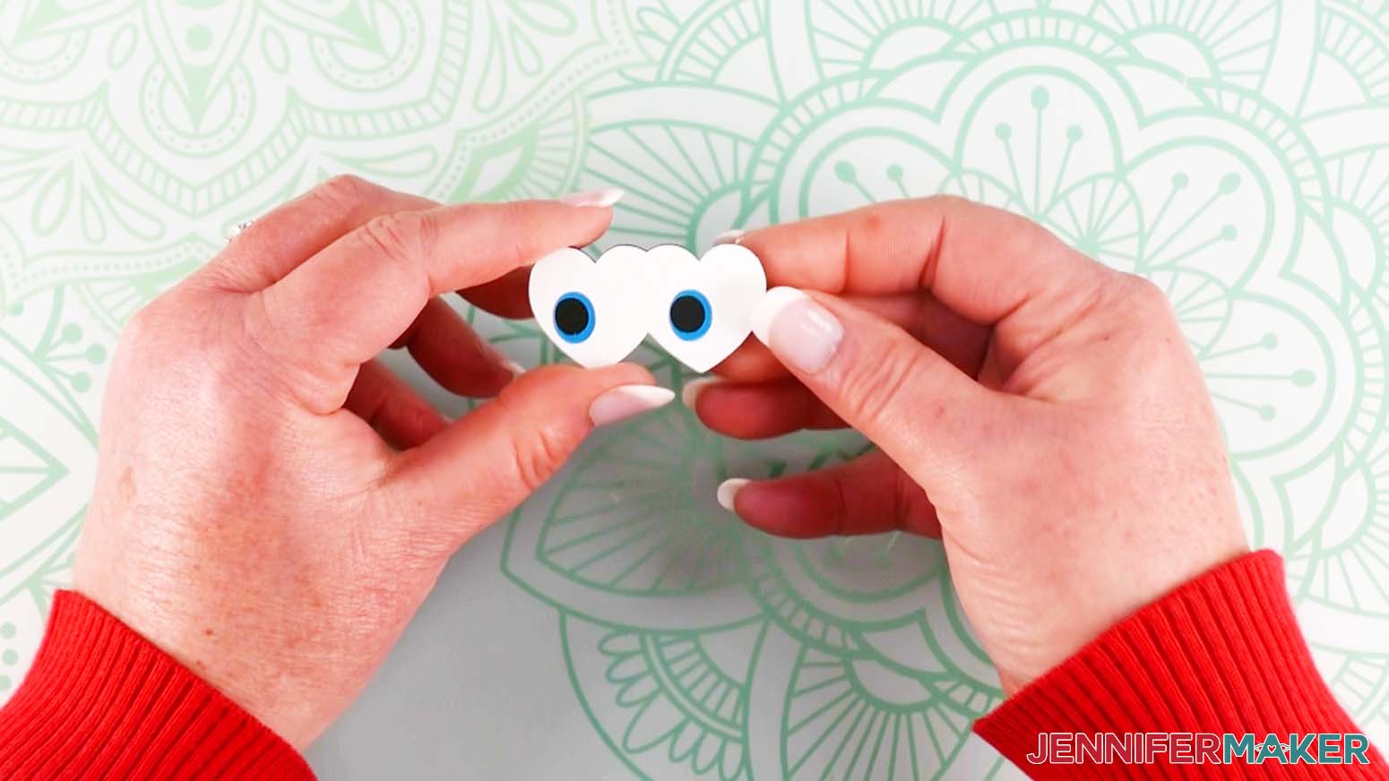 Crafter holding aligned and stacked black, blue, and white heart-shaped layers for chick DIY lollipop holders.