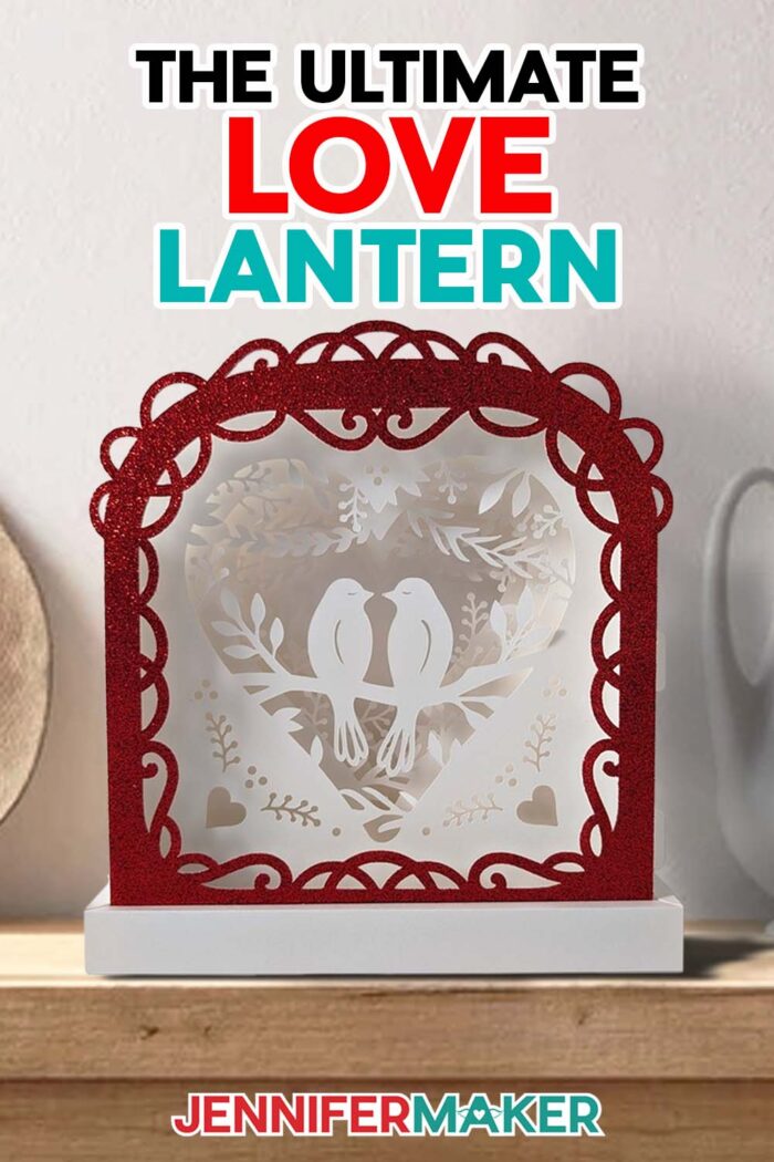 Make the Ultimate Love Lantern with this JenniferMaker tutorial! A white cardstock lantern with a glittery red frame and two love birds in the middle sits on a mantel.