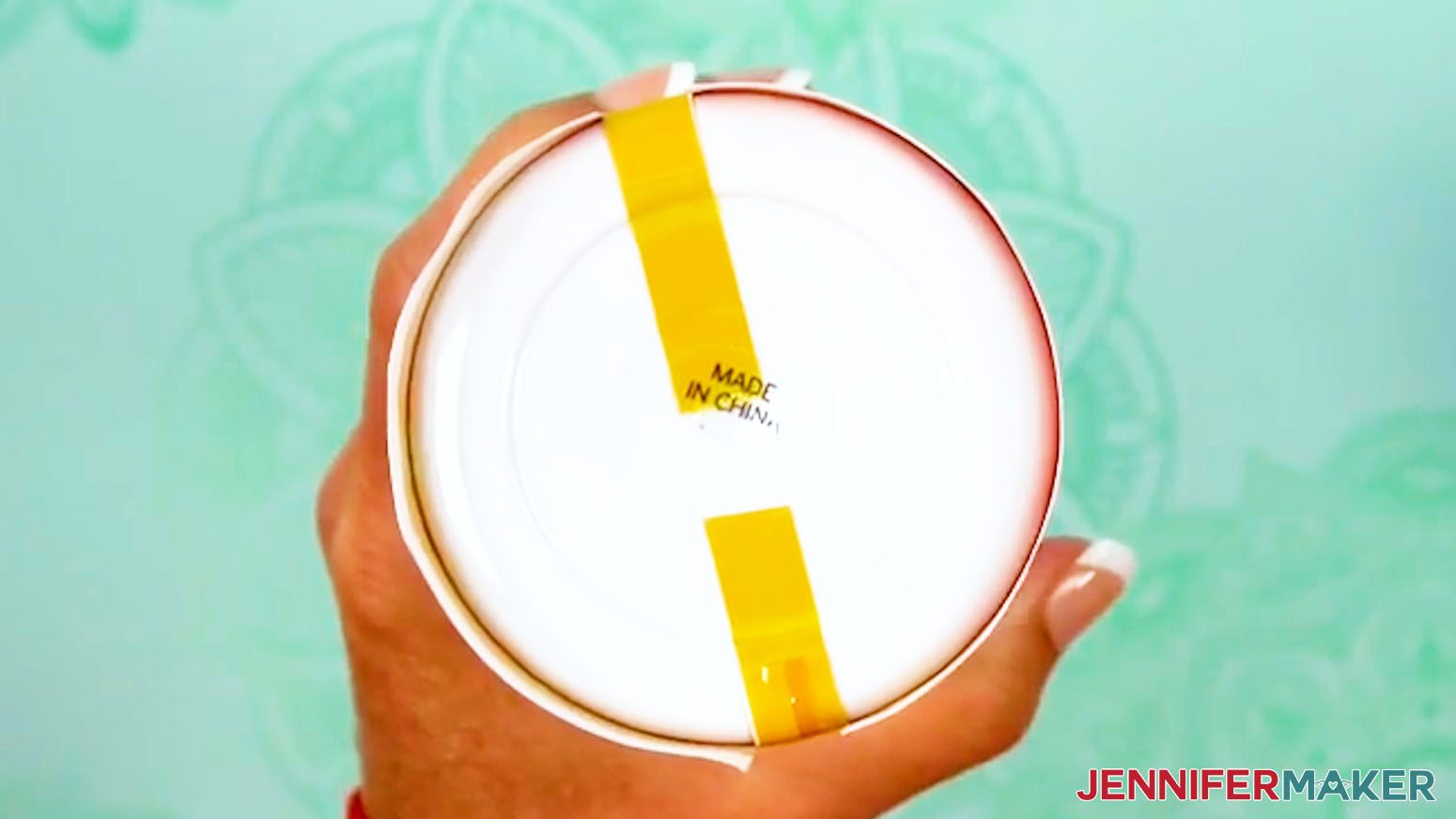 Press the opposite piece of tape onto the bottom of the sublimation design tumbler.