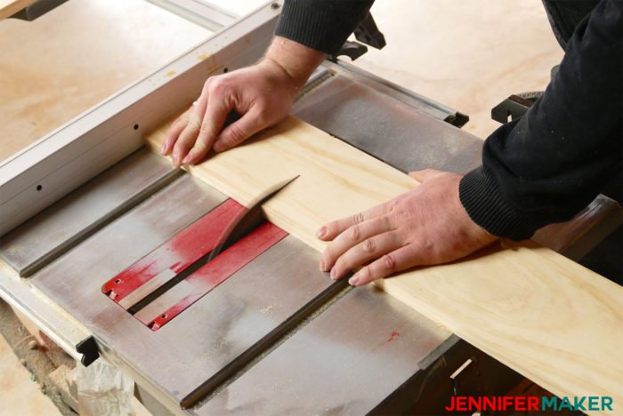 Cutting the marked 3/4" thick pine board on a table saw to make birdhouses