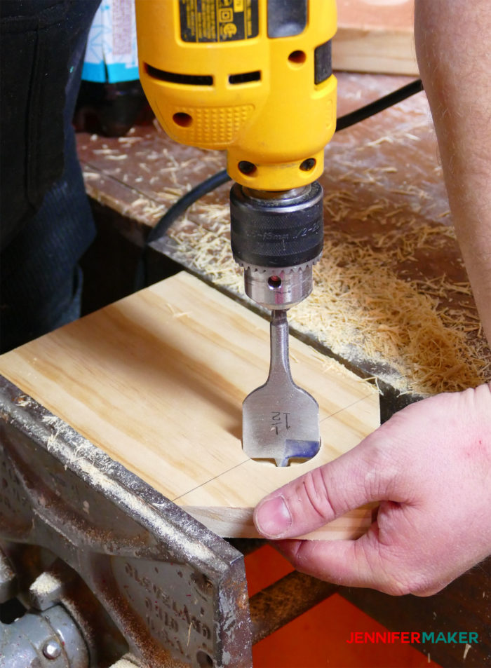 Drilling a hole in the front of the birdhouse with a 1 1/2" bit using a power drilll