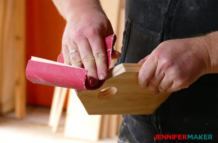 Sanding a birdhouse part with sandpaper to make a DIY birdhouse