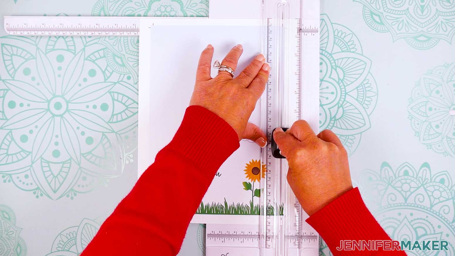 Press the ruler down on the paper trimmer to hodl it in place and slide the blade along the side of the card to cut off the excess paper.