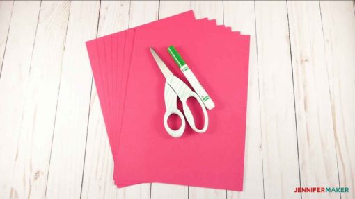 Pink paper and scissors, ready to cut and make giant paper flowers