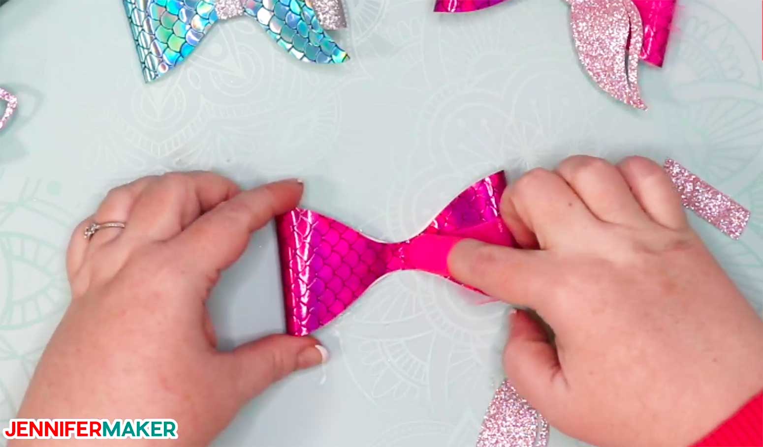 Gluing folded pink tulle to a bow to make hair bows with mermaid tails