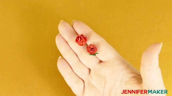 Two miniature paper roses made from red cardstock in a hand