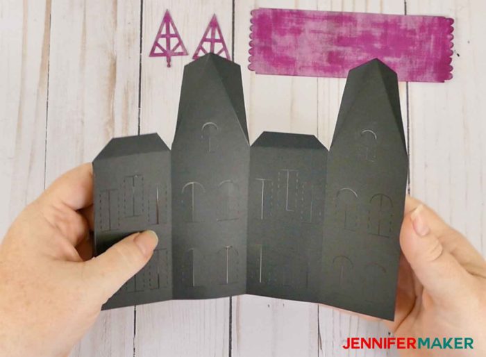 A folded black piece of paper is the first step to to make paper haunted houses and a village