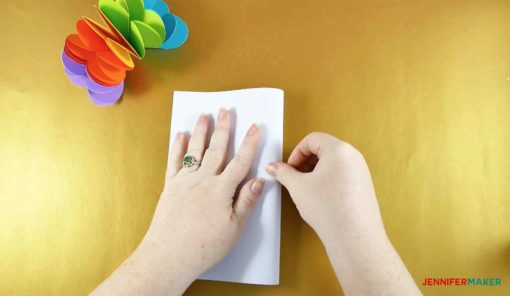 Folding a white piece of cardstock in half to make the pop-up heart card