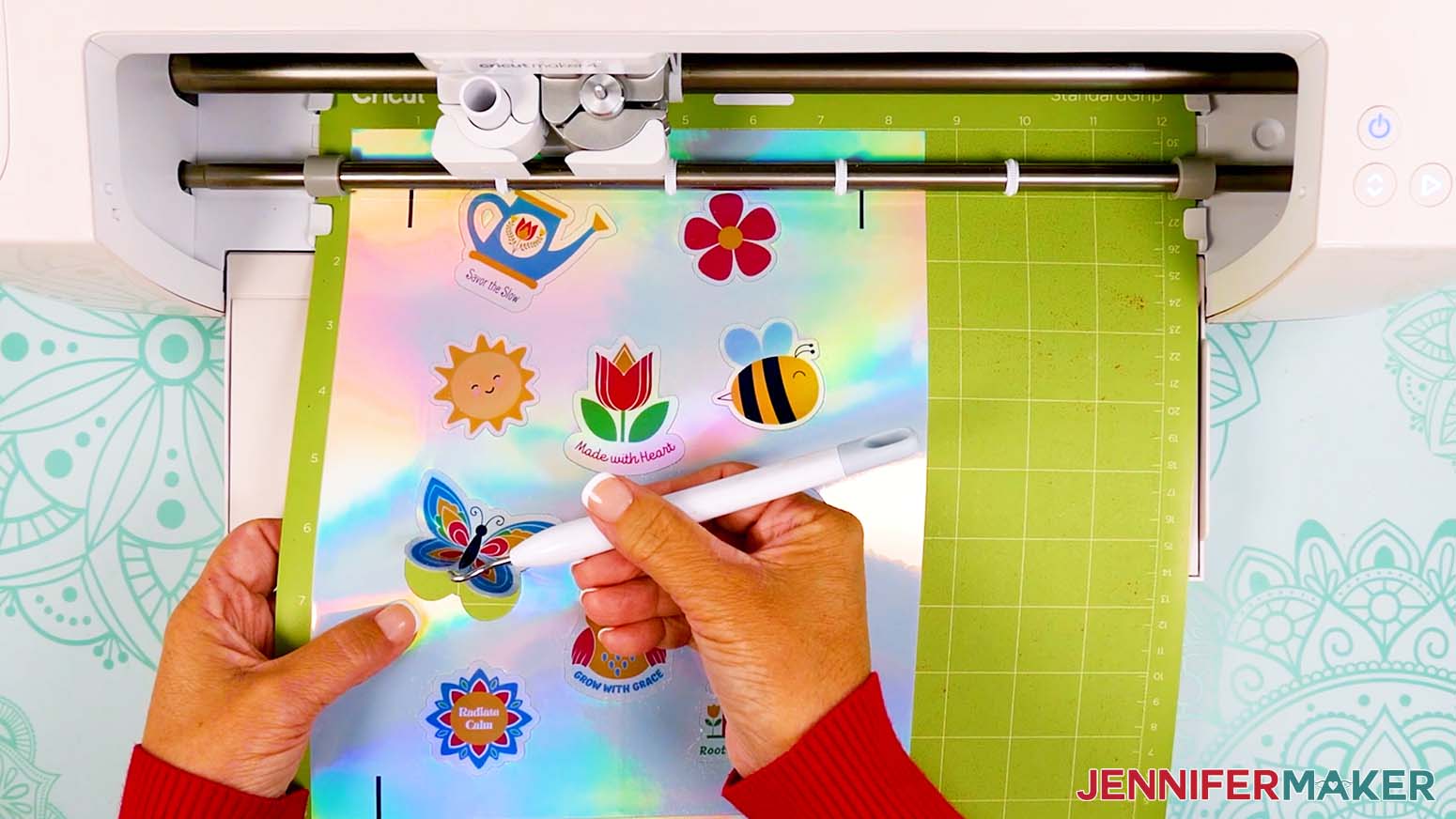 The sticker sheet has been cut out and is still loaded into the Cricut. The butterfly sticker is being lifted off the sheet with a weeding tool.