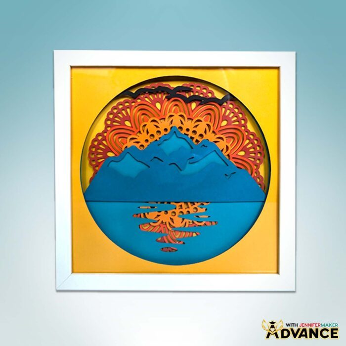 Design a custom mandala sunset shadow box with the Advance with JenniferMaker program at jennifermaker.com/advance! A  mandala design featuring a sunset over the mountains with a lake.