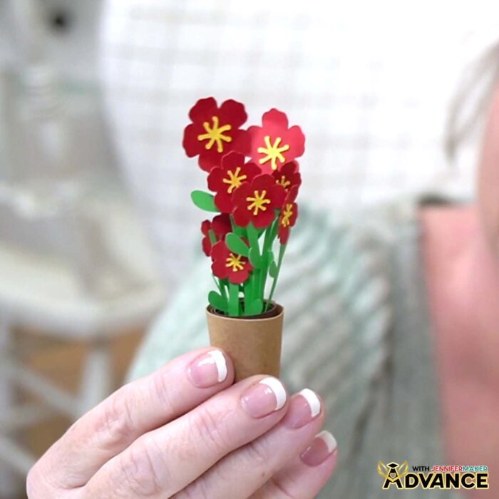 A hand holds a mini blossom mini flower arrangement in a paper pot from JenniferMaker's Mini Paper Flower Tutorial