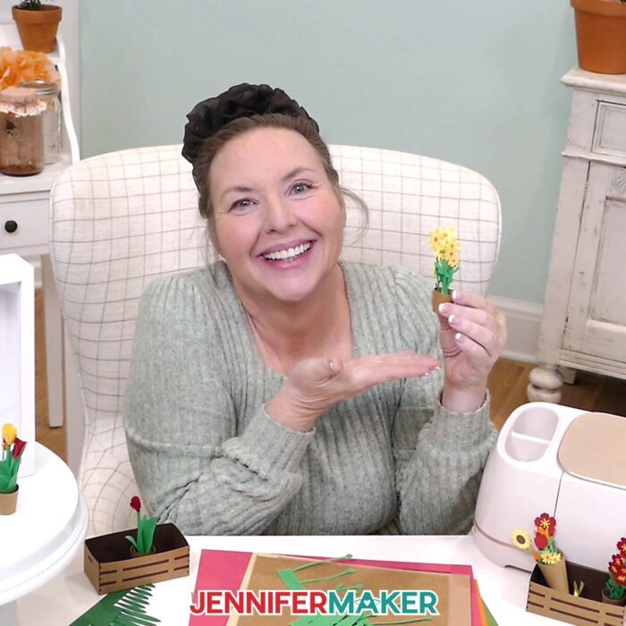 Jennifer Maker sits at her craft table, showing off a mini potted plant from her Mini Paper Flower Tutorial