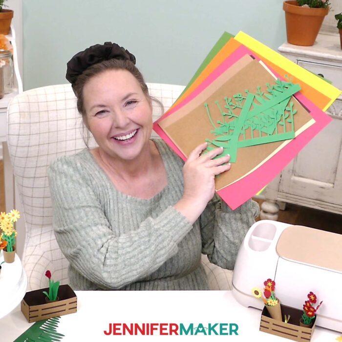 Jennifer Maker sits at her craft table, showing off the supplies to make miniature flowers and plants from her Mini Paper Flower Tutorial