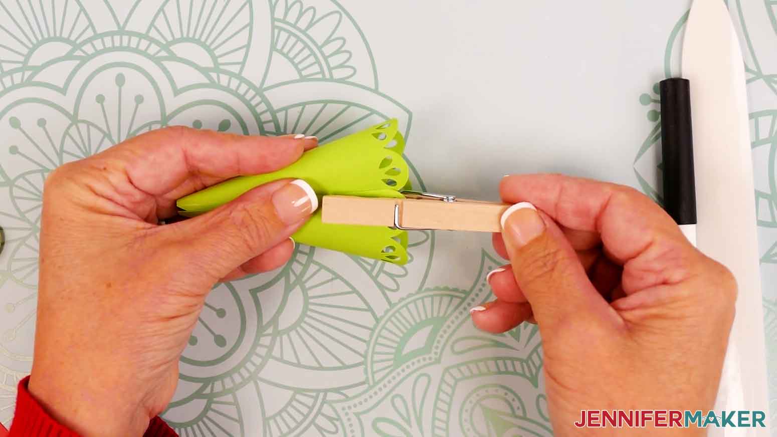 Align the tree piece&rsquo;s straight edge along the crease line on the outside of the cardstock, and use a clothespin to hold the bottom half in place.
