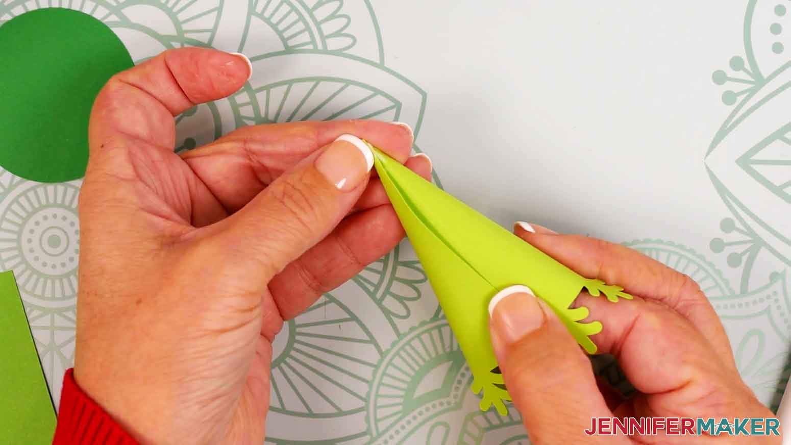 Use your fingers to curl the tree piece&rsquo;s edge around the pointed tip to align it with the crease line, then press and hold the cardstock together.