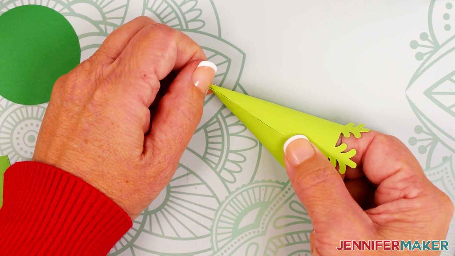 Press and hold the glued cardstock where it overlaps on the tree piece&rsquo;s bottom half, keeping the edge aligned with the crease line.