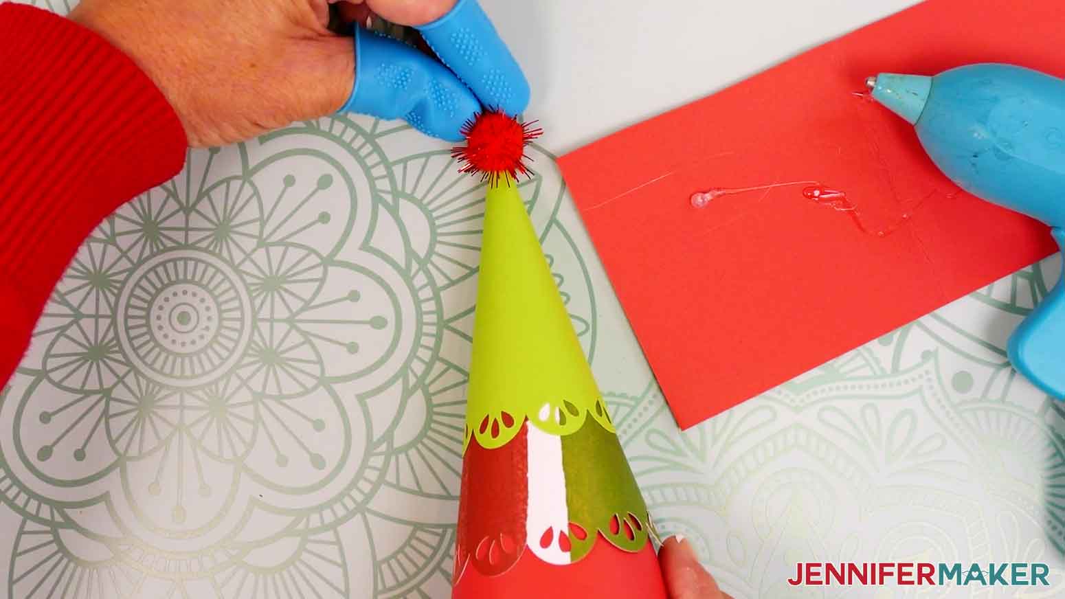 Position a pom pom on top of the tree, then hold it by the sides between your protected fingers.