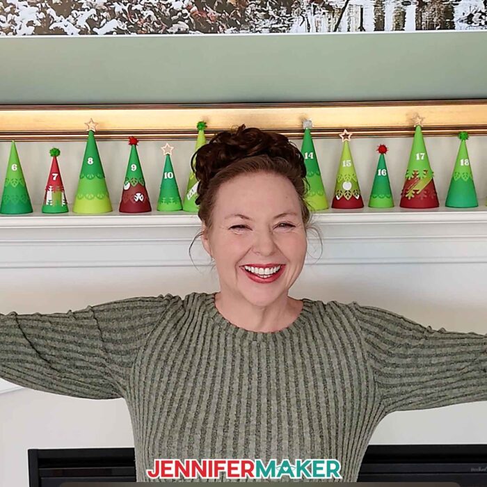 Jennifer Maker shows off the Minimalist Tree Advent Calendar project on her fireplace mantel, made up of colorful cone-shaped tree boxes made from cardstock
