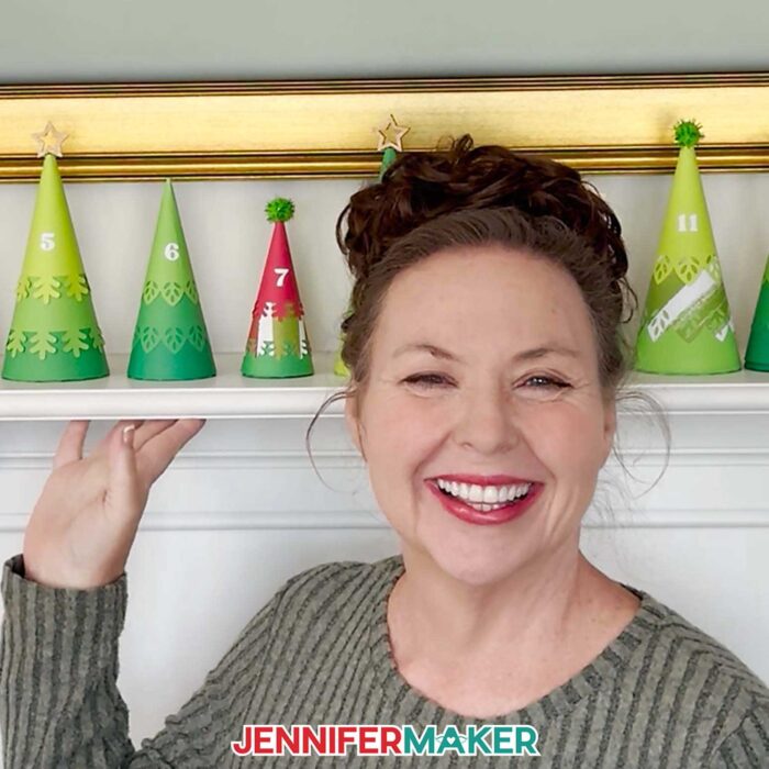 Jennifer Maker shows off the Minimalist Tree Advent Calendar project on her fireplace mantel, made up of colorful cone-shaped tree boxes made from cardstock