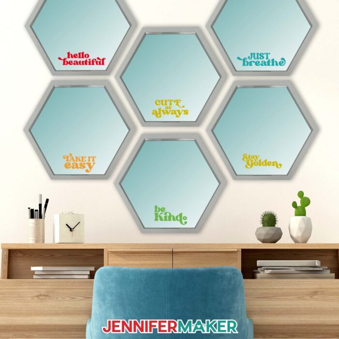 Six silver hexagonal mirrors with encouraging messages cut from Cricut Value Vinyl hang above a desk.