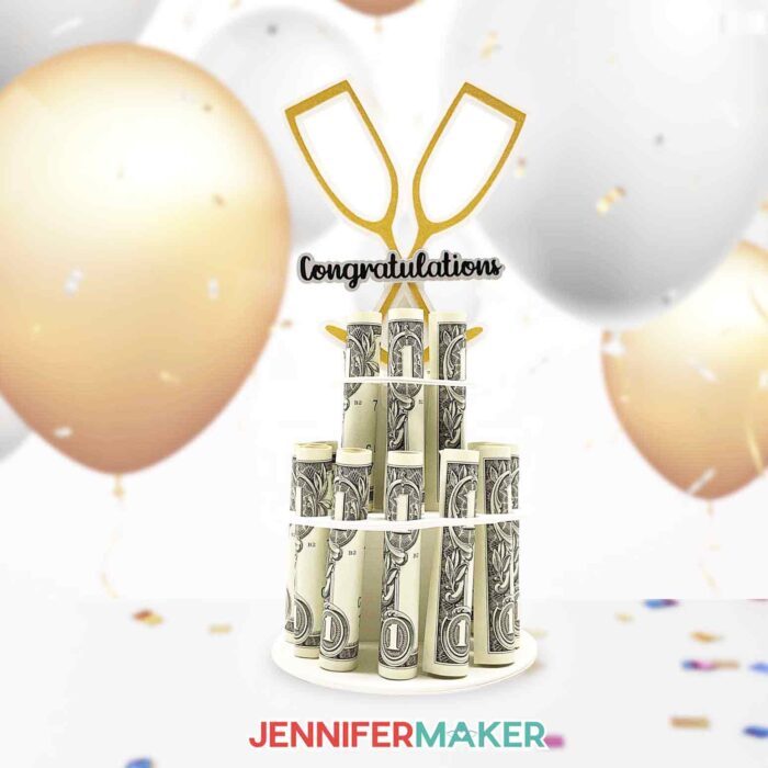 Gold, white, and silver money cake decoration with crossed champagne flutes and Congratulations in black, holding rolled dollar bills in a two-tier column.