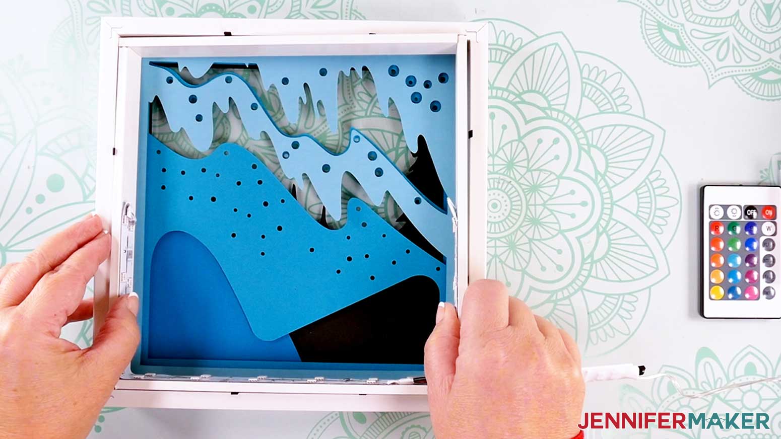 Inserting the cardstock layers into the frame to make a Northern Lights Shadow Box