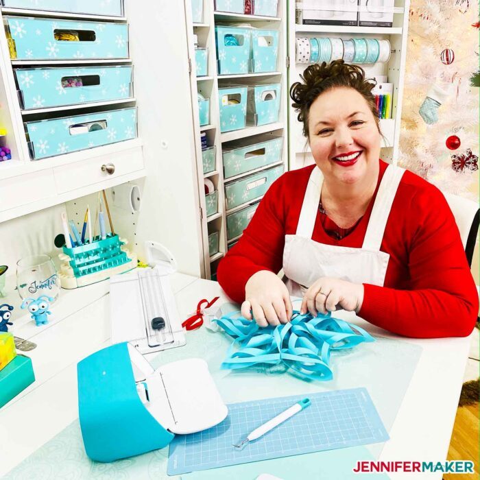 Jennifer sitting at her organized DreamBox with a blue paper snowflake and the Cricut Joy