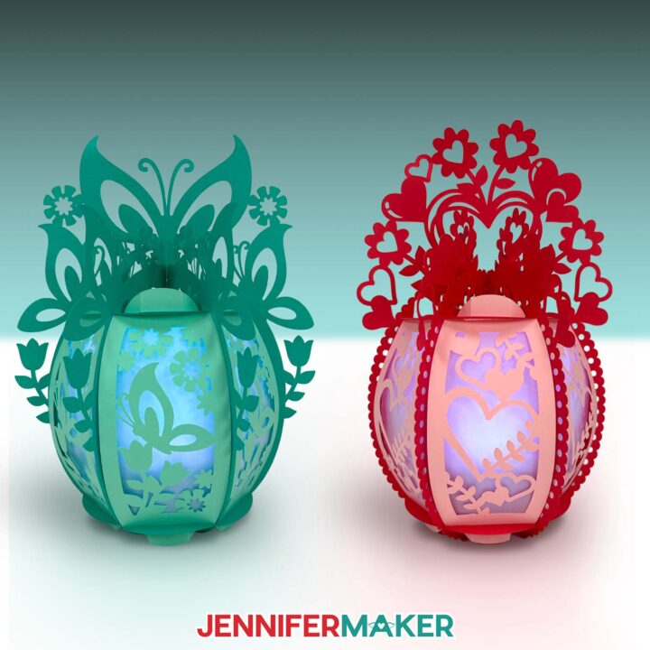 Two finished ornate 3D paper lanterns, one with butterfly embellishments and one with hearts.
