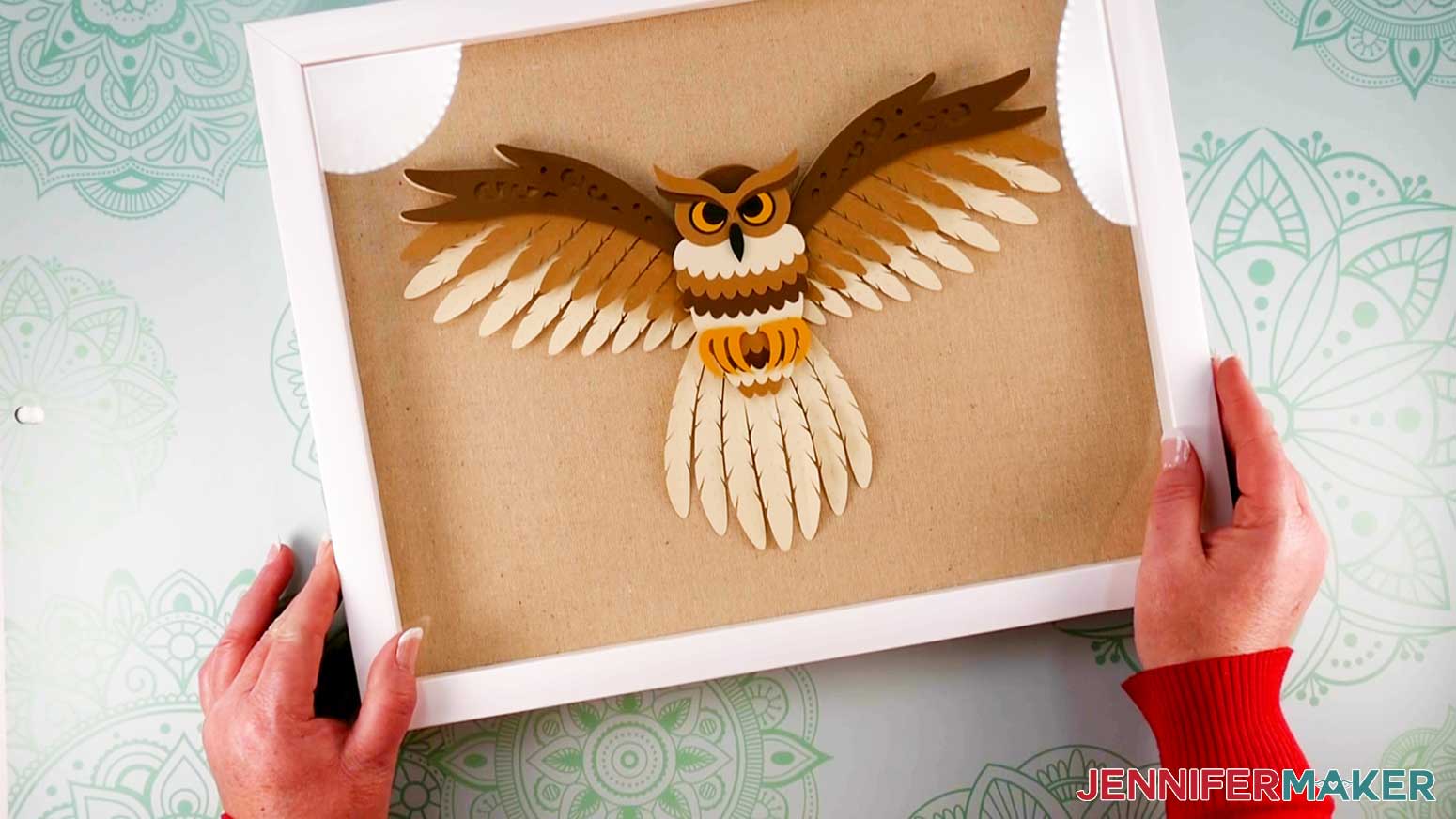 An overhead photo of the finished layered owl displayed in a shadow box with a white frame