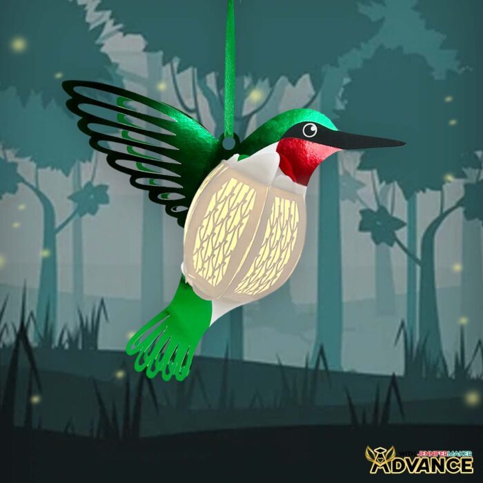 A hummingbird Paper Animal Lantern uses LED lights inside to glow against a moody forest scene. 