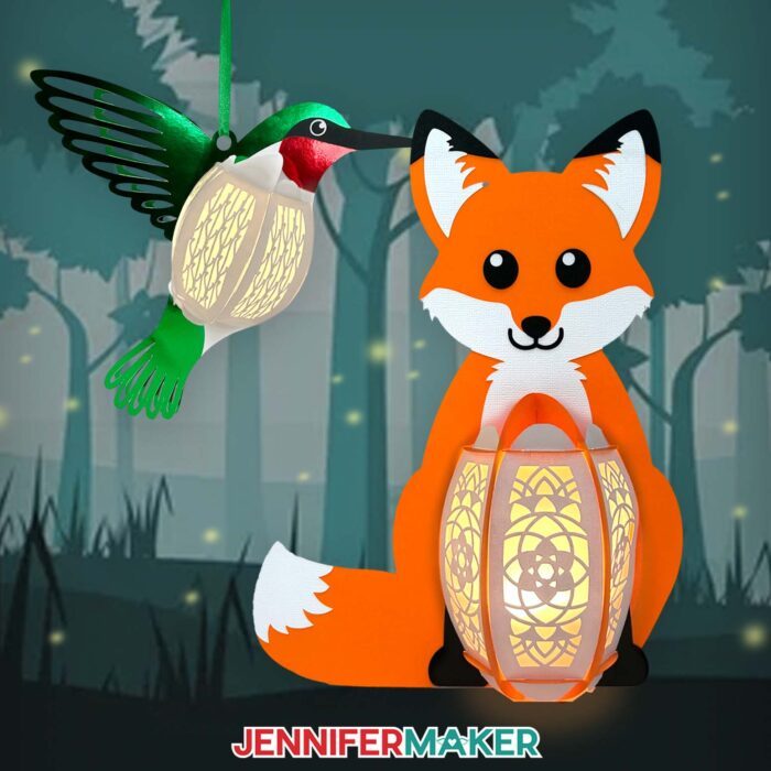 One orange fox and one metallic green hummingbird Paper Animal Lantern light up in a dark wooded scene