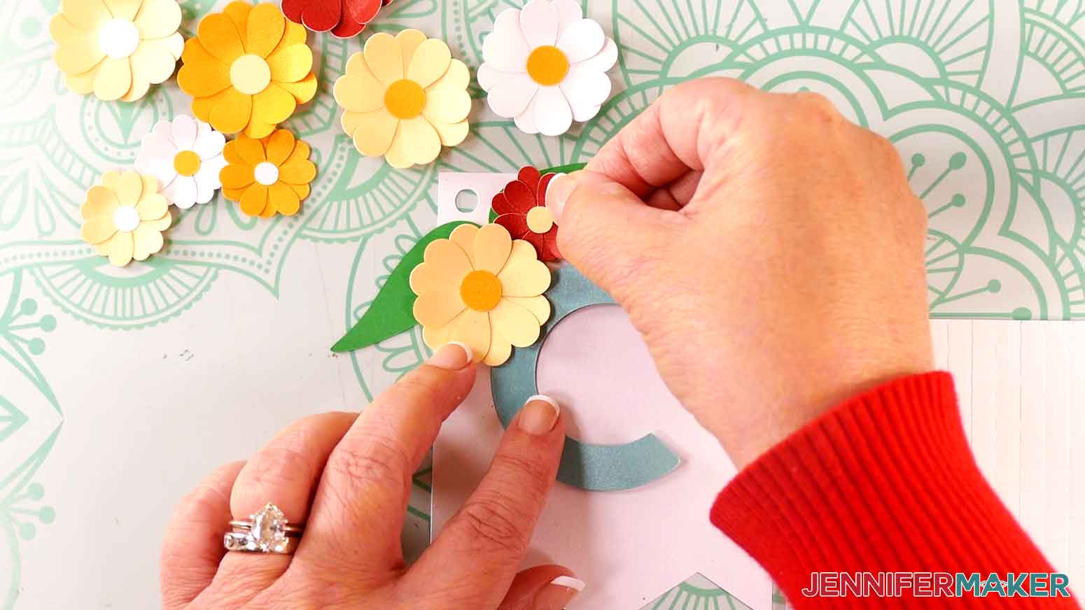 Place the smaller red flower next to the yellow flower over the upper right leaf.