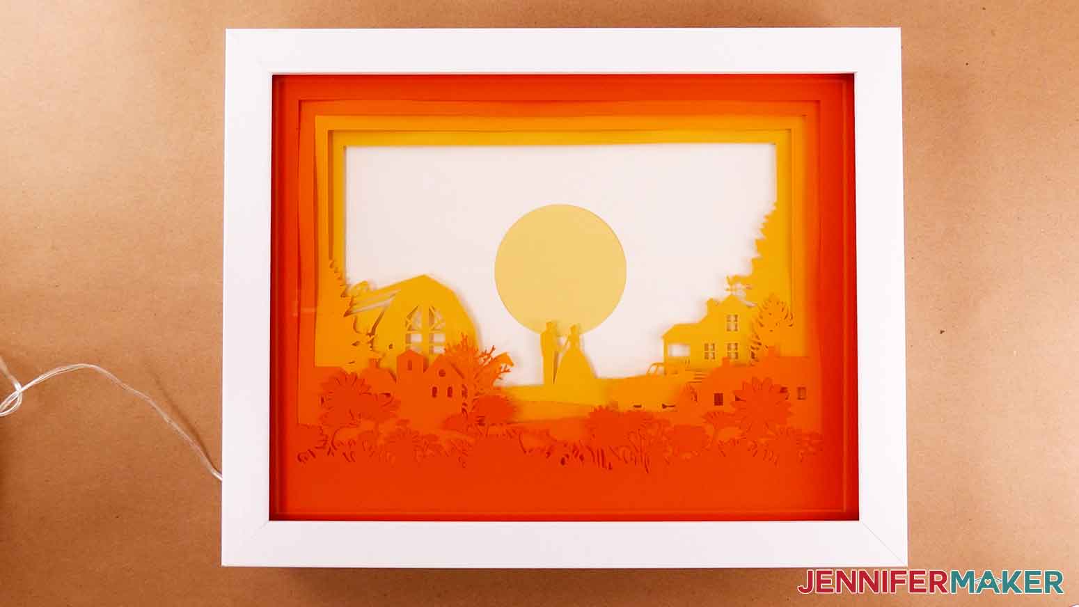 A finished paper cut light box with colored layers inside a purchased glass shadow box