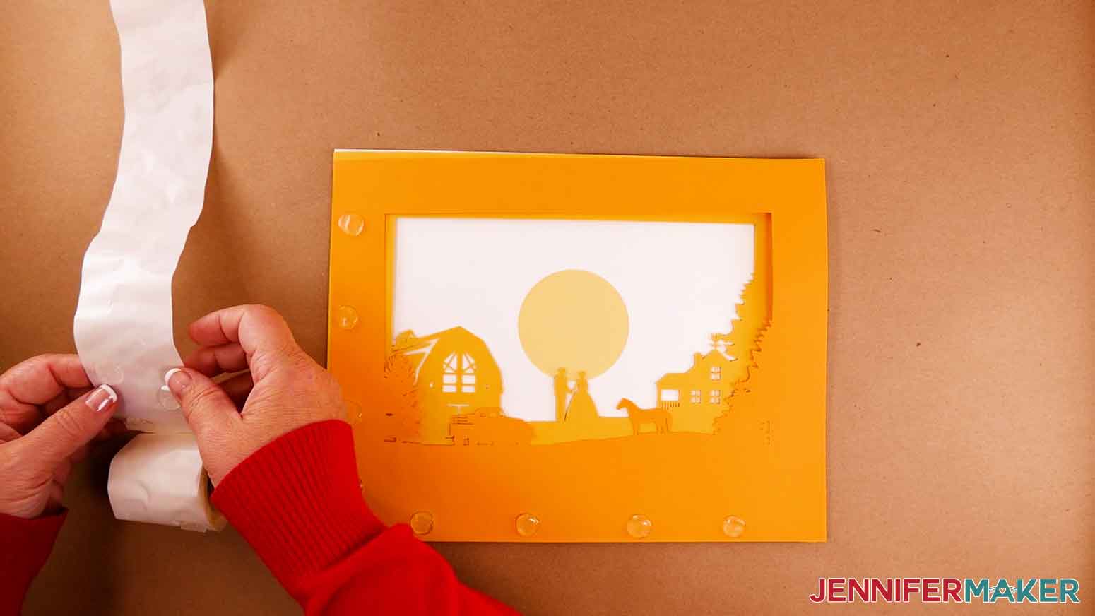 Placing 3D glue dots on the back of layer C for the paper cut light box tutorial