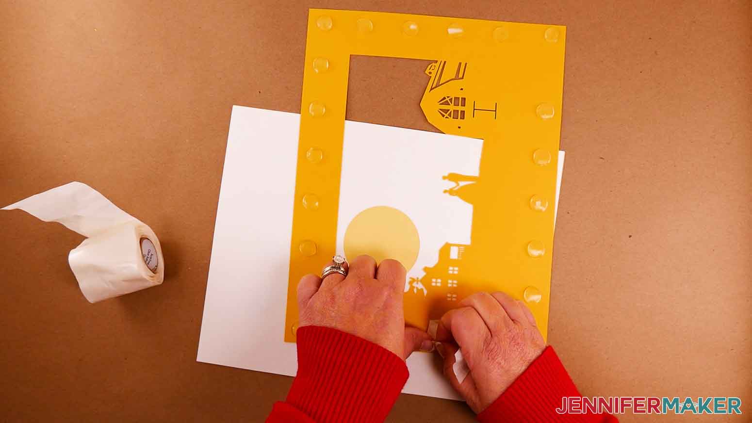 Placing 3D glue dots on the back of layer D for the paper cut light box tutorial