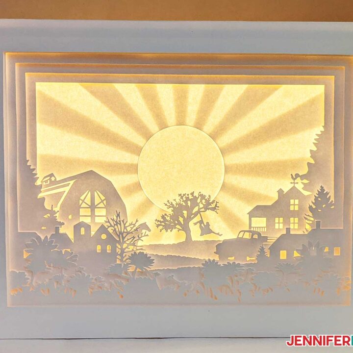 A finished paper cut light box with white layers inside a shadow box