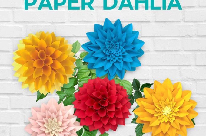 Multicolored paper dahlias on a gray brick background.