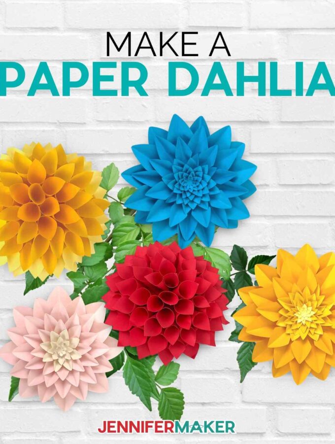 Multicolored paper dahlias on a gray brick background.
