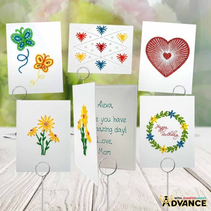 The full collection of Paper Embroidery Cards sits on display on a white picnic table. One of the cards with yellow flowers on the front is partially open to reveal a message inside written with a Cricut