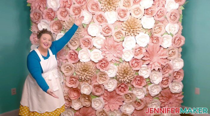 Crafter showing the completed paper flower backdrop in pinks and greens, large enough for group photos.