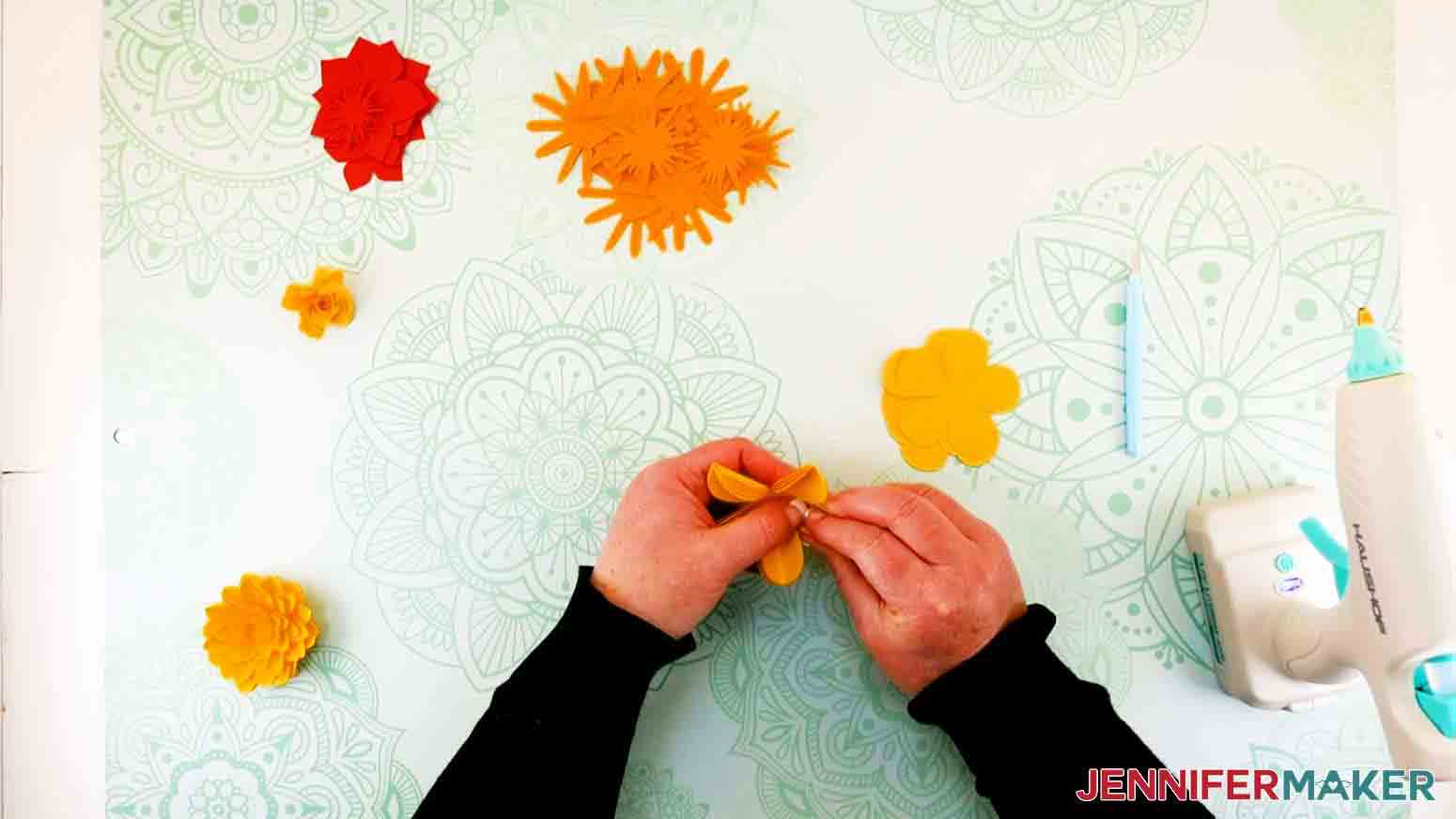 shows hands pinching petals of a layered rose paper flower letter