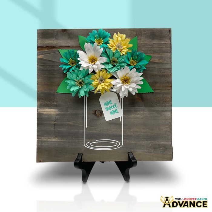 Learn how to create a beautiful paper flower sign with JenniferMaker's tutorial! An Advance paper flower sign with a customized tag sits on a surface. 
