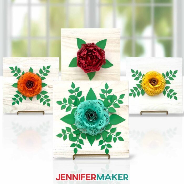 Four paper flowers with lace petals on wood signs: A red peony with heart lace petals, a teal rose with scalloped lace petals, a yellow rose with heart lace petals, and an orange rose with custom lace petals. Design by JenniferMaker.