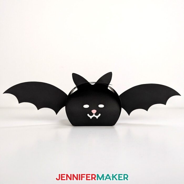 Learn how to make easy Paper Halloween Treat Boxes with JenniferMaker's tutorial! A cardstock and vinyl treat boxes in the shape of a bat sits on display.