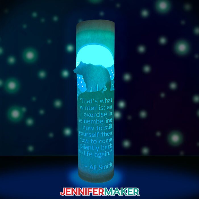 Learn how to make layered paper lanterns with lights with Jennifer Maker's tutorial! An illuminated paper lantern with a bear and custom quote glows against a starry background.