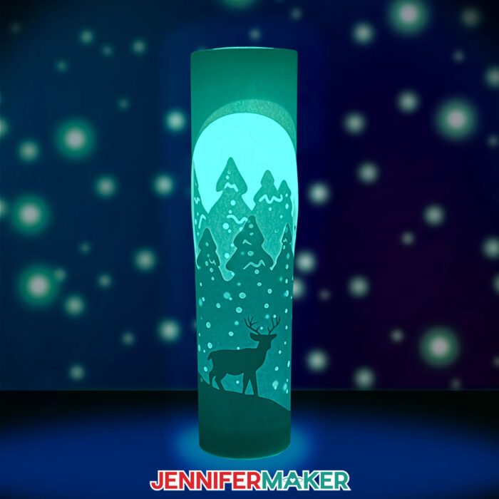 Learn how to make layered paper lanterns with lights with Jennifer Maker's tutorial! An illuminated paper lantern with a deer glows against a starry background.