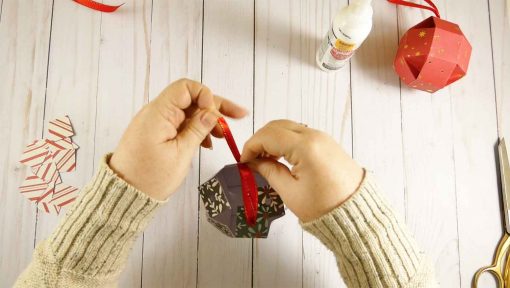 Push the ribbon through the hole in the tabs at the top of your paper orb