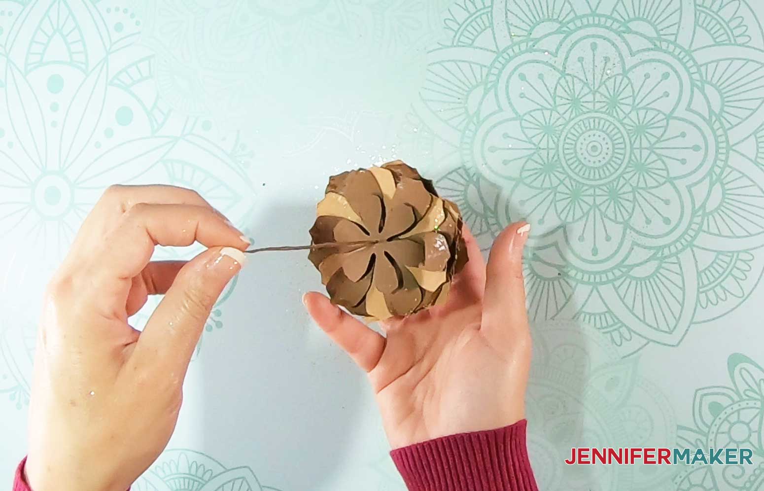 Thread paper pinecone base onto stem