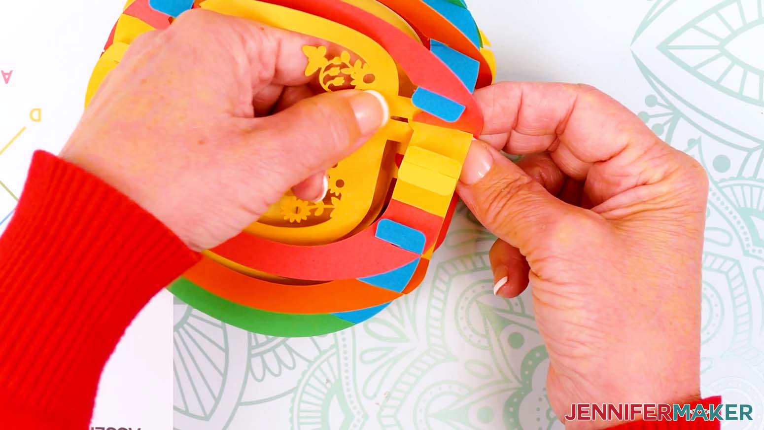 Pinch the front bottom bump from the outside of the paper pop up Easter egg's shell to insert the front scene layer's bottom tab.